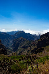 Breathtaking mountain valley view on Madeira Island, showcasing rugged peaks, green hills, and deep shadows on a sunny afternoon.
