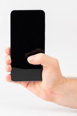 Hand holding smartphone against plain background during daytime