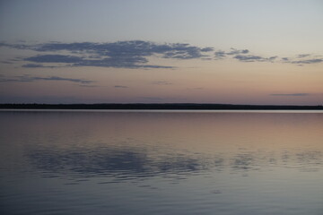 Quiet evening after a sultry day. Beautiful sunset over the lake. Reflection and horizon. Evening dim soft sun