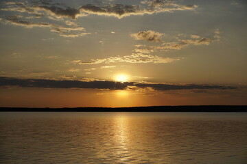 Quiet evening after a sultry day. Beautiful sunset over the lake. Reflection and horizon. Evening dim soft sun