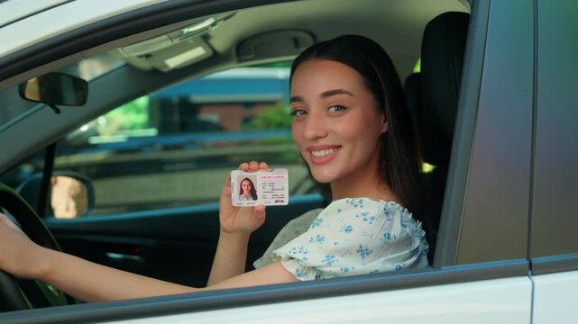 Smiling happy Caucasian driver school student female woman girl car owner sitting inside automobile window looking camera smile showing driving license courses pass exam rental service buying vehicle