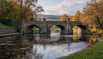 A Historic Stone Bridge Spanning Over A Gentle River With Autumn Trees Nearby