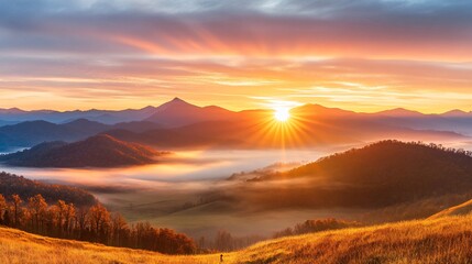 Obraz premium Breathtaking Sunrise Over a Mountain Range Illuminating Misty Valleys Below