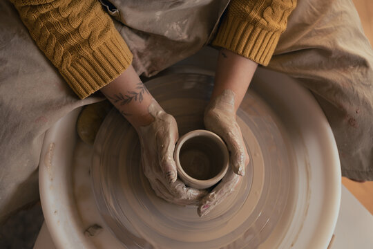 Hands of woman working with pottery wheel. Top view