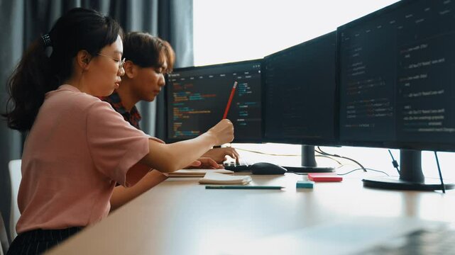 Slow motion back end software developer engineer for computer programming working together on debugging writing computing code, solving complex algorithms display on monitor in office. Burgeoning