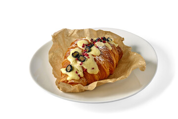 delicious croissant with butter cream and berries on white ceramic plate isolated on white background