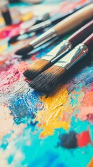 Obraz premium Colorful paint splatters with various brushes on a creative workspace.