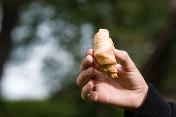 Hand holding a small pastry outdoors