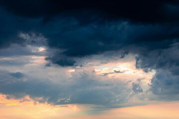 Dramatic pre-storm sky with orange hues blending into dark blue clouds. Atmospheric scene before storm