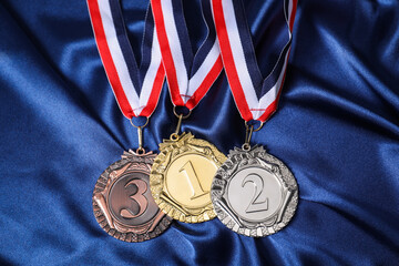 Golden, silver and bronze medals on blue fabric, above view