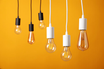 Light bulbs hanging on cords against orange background