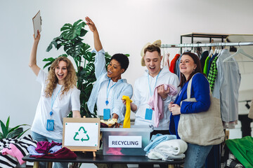 Group of volunteers, young women and man, sorting clothes in charitable foundation for charity donation, recycling. Concept of textile pollution, conscious consumption. Ecology, sustainable lifestyle