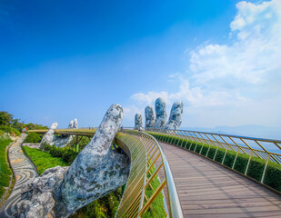Golden Bridge in Ba Na hills, Da Nang, Vietnam on a sunny day. Lifted by two giant concrete hands. Iconic world famous bridge in the mountains