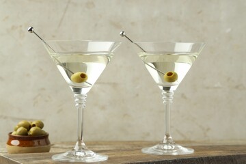 Martini cocktail with olives in glasses on wooden table