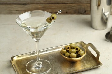 Martini cocktail with olives in glass and shaker on light table