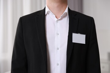 Man with blank badge indoors, closeup view