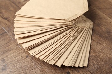 Many paper coffee filters on wooden table, closeup