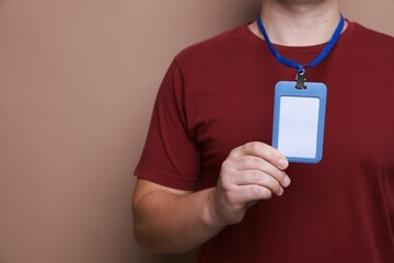 Man with blank badge on brown background, closeup. Space for text