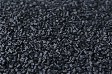 Pile of black plastic granules as background, closeup