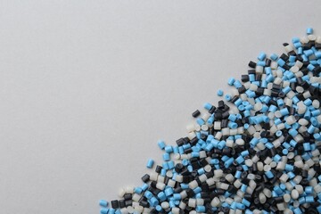 Pile of colorful plastic granules on grey background, top view. Space for text