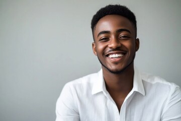 Bright smile of a young man in a casual setting exuding confidence and warmth with a backdrop of soft neutral tones highlighting his joyful expression