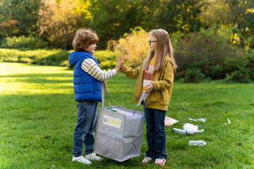 Boy and girl collecting garbage in park supporting environmental care in camp