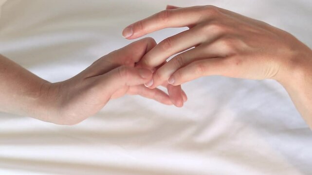 Same-sex relationships, lesbians. Same-sex marriage and love concept. Happy lesbian couple. Two female hands touching each other against white sheets. Two female hands in bed close-up. LGBTQ