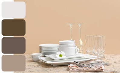 Composition with clean dishes, chamomile, glasses and cutlery on table near beige wall