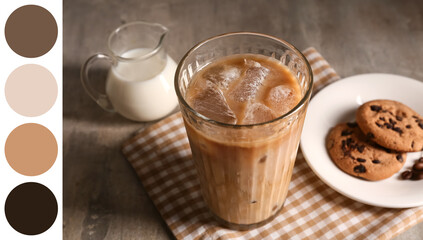 Glass of iced latte and plate with sweet cookies on grey background