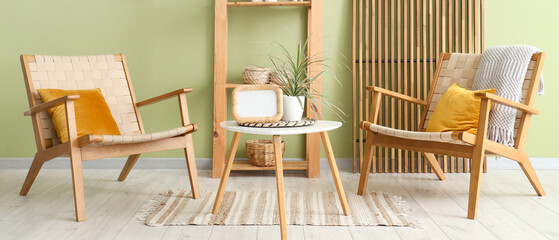Interior of modern room with comfortable armchairs, shelving unit and coffee table near green wall