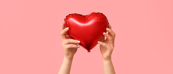 Obraz premium Woman with air balloon in shape of heart on pink background. Valentine's Day celebration