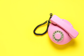Pink retro telephone on yellow background