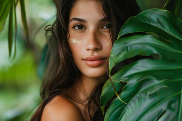 Papier peint photo intissé Portrait of a beautiful young woman, surrounded by lush tropical leaves, embodying natural beauty and exotic freshness.