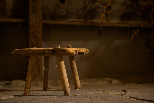 Wooden stool with three legs is sitting on the ground