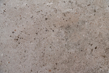 Aged cement wall with coarse texture and scattered dark patches