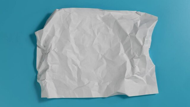 Stop motion animation of crumpled pape on a blue background. High quality 4k footage