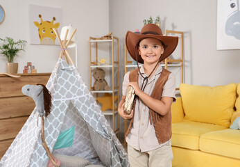 Cute little cowboy with book at home
