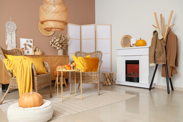 Interior of stylish living room with wicker armchairs, fireplace and autumn decor