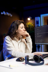 Freelancer doing software debugging using computer, checking errors in lines of code displayed on...