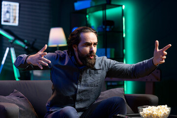 Excited fan watching live sports event on TV, whistling and chanting for team. Supporter at home doing energetic hand gesturing, cheering for own club to triumph in competition