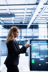 Software developer using tablet in data center with advanced tech, ensuring cybersecurity and...