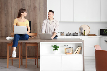 Young couple using laptops in kitchen