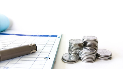 Close-up of stacked silver coins on a table, alongside a pen and invoice sheet, symbolizing money management and budgeting.