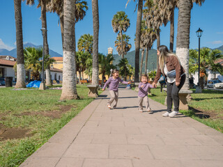 Latina mother plays with her daughter in the city square.