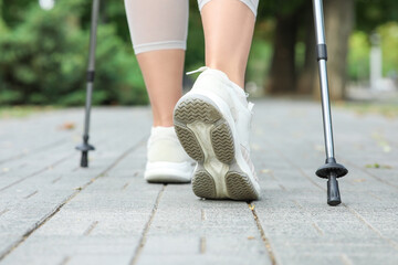Sporty woman doing Nordic walking on street, closeup