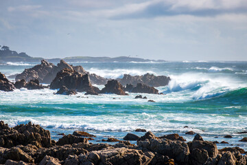 Scenic view rocky Pacific Ocean coast along 17-Mile-Drive looking south, Del Monte Forest, California, USA against blue sky with clouds
