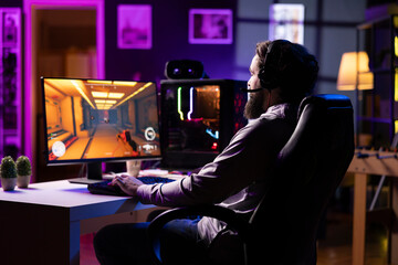 Man playing science fiction FPS videogame, having fun in dark cozy apartment room. Gaming enthusiast competing in PvP online multiplayer game, shooting other players with futuristic gun laser bullets