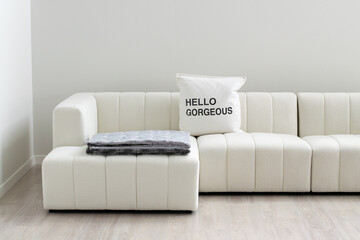 Minimalist living room with white sectional sofa and 'Hello Gorgeous' pillow