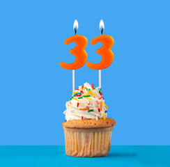 Orange candle number 33 - Birthday cupcake on blue background