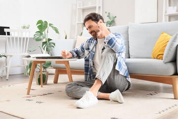 Young man with drops suffering from ear pain at home